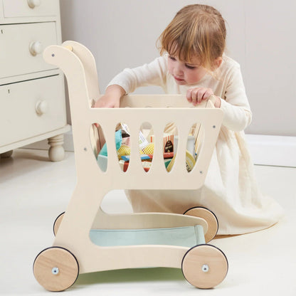 Child playing with a wooden toy cart in a room with white furniture.