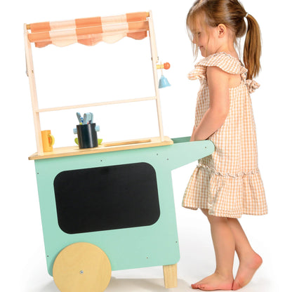 Child playing with a toy kitchen cart on a white background