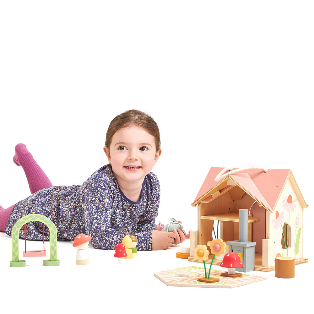 Child playing with a wooden dollhouse and accessories on a white background
