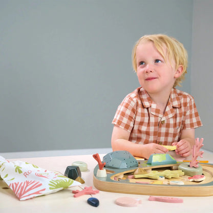 Child playing with a wooden toy set on a table against a gray background