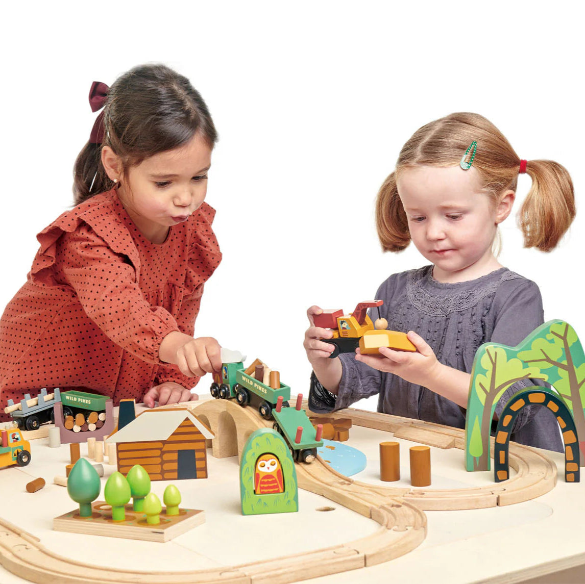 Two children playing with a wooden train set on a white background