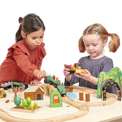 Two children playing with a wooden train set on a white background