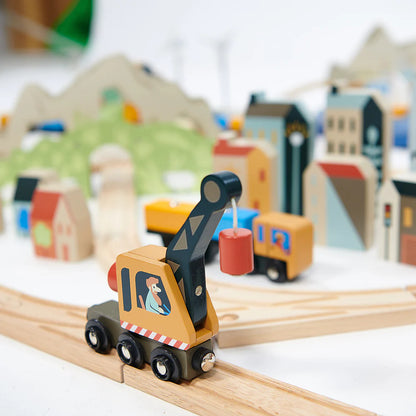 Wooden toy crane on a track with a blurred model cityscape in the background