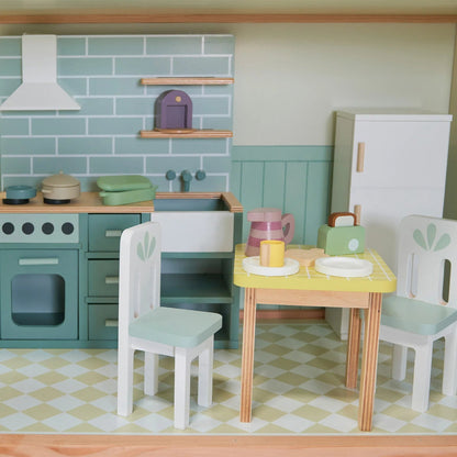 Miniature kitchen set with table, chairs, and appliances in a dollhouse-like setting.