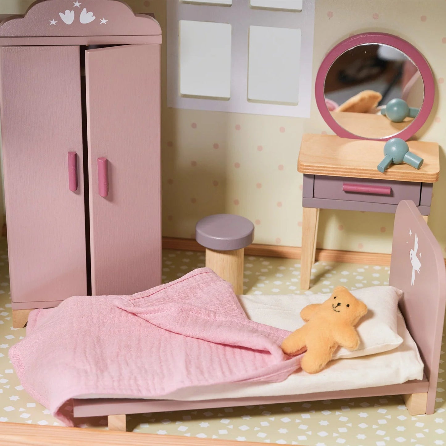 Dollhouse bedroom with pink wardrobe, bed, and vanity table.