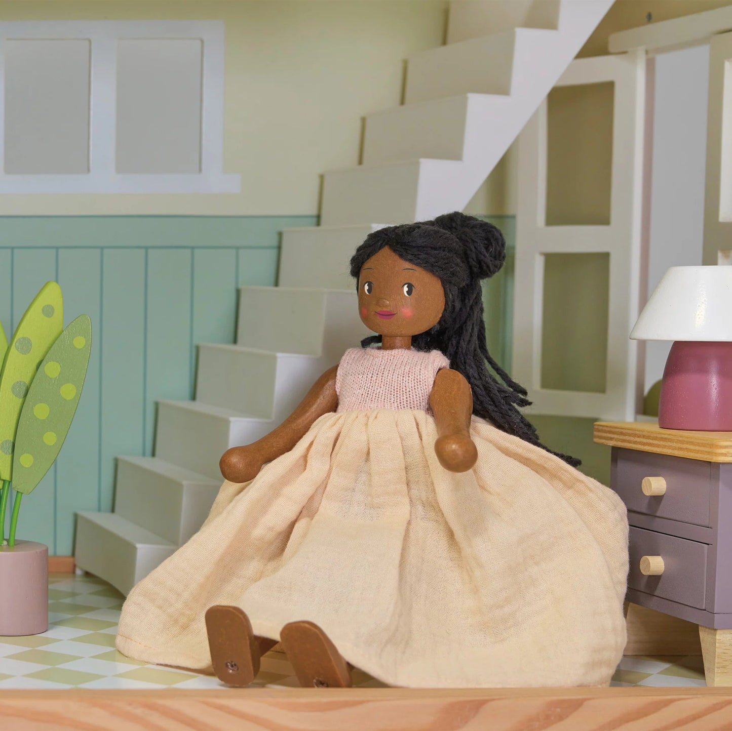 Doll in a room with a staircase, lamp, and plant