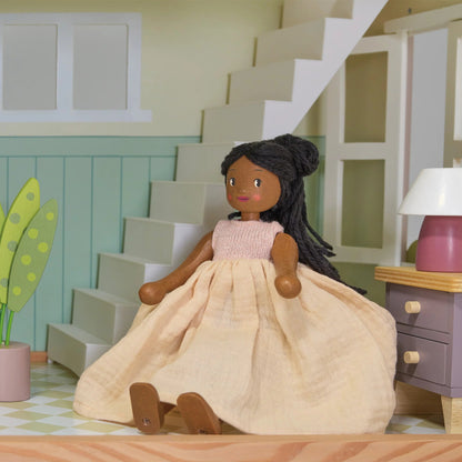 Doll in a room with a staircase, lamp, and plant