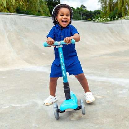Child riding a blue scooter at a skate park