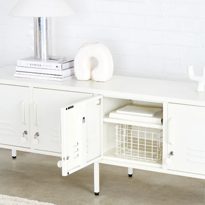 White cabinet with open door revealing a basket inside, on a light wooden floor.