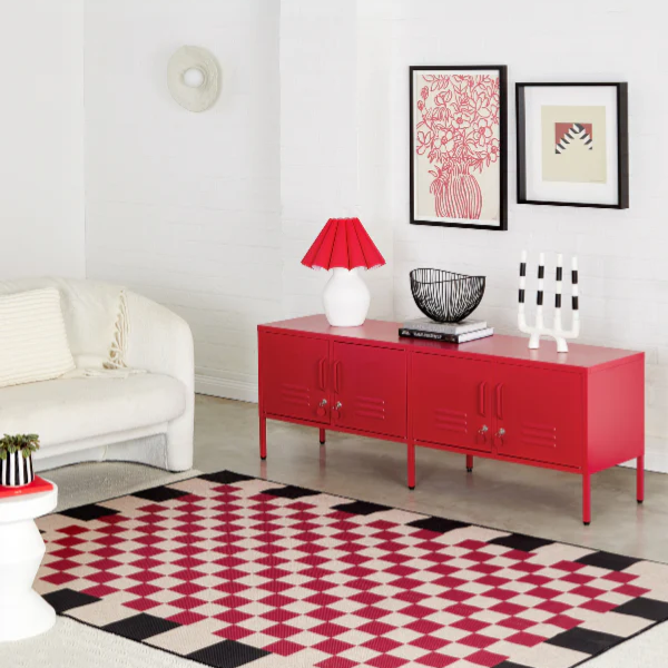 Modern living room with a red sideboard, white sofa, and geometric rug.
