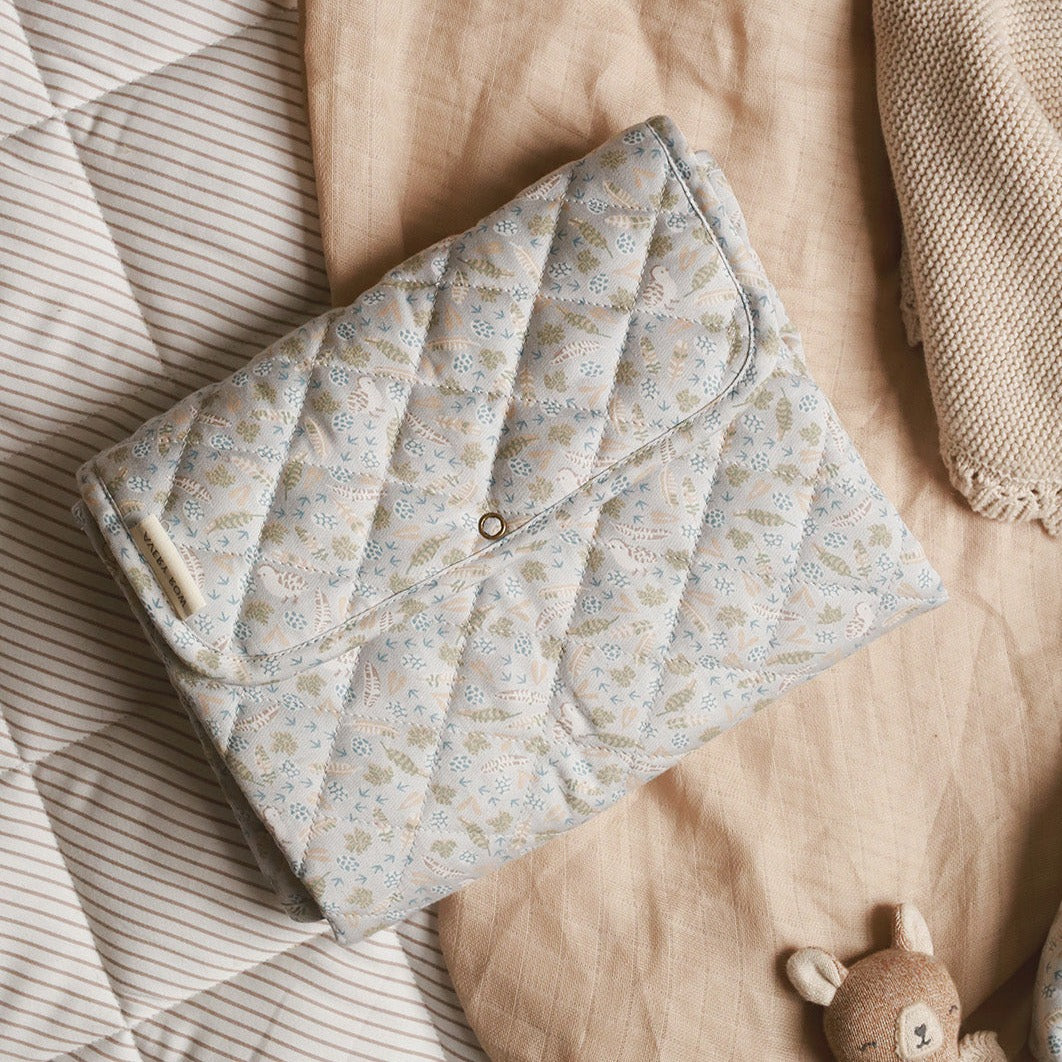 Floral-patterned quilt on a bed with a plush toy