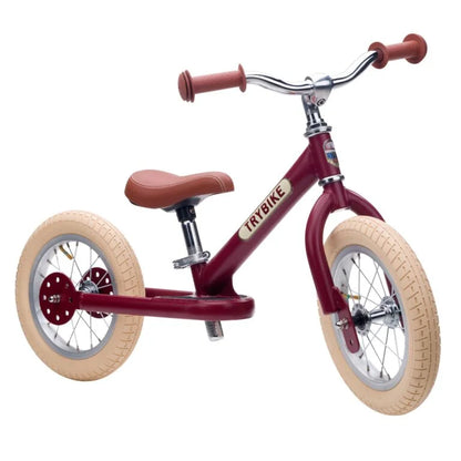 Red balance bike with beige tires on a white background
