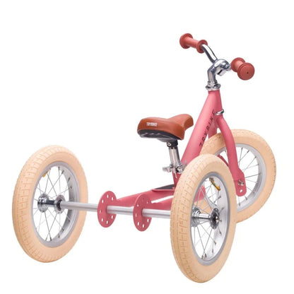 Pink balance bike with tan wheels on a white background