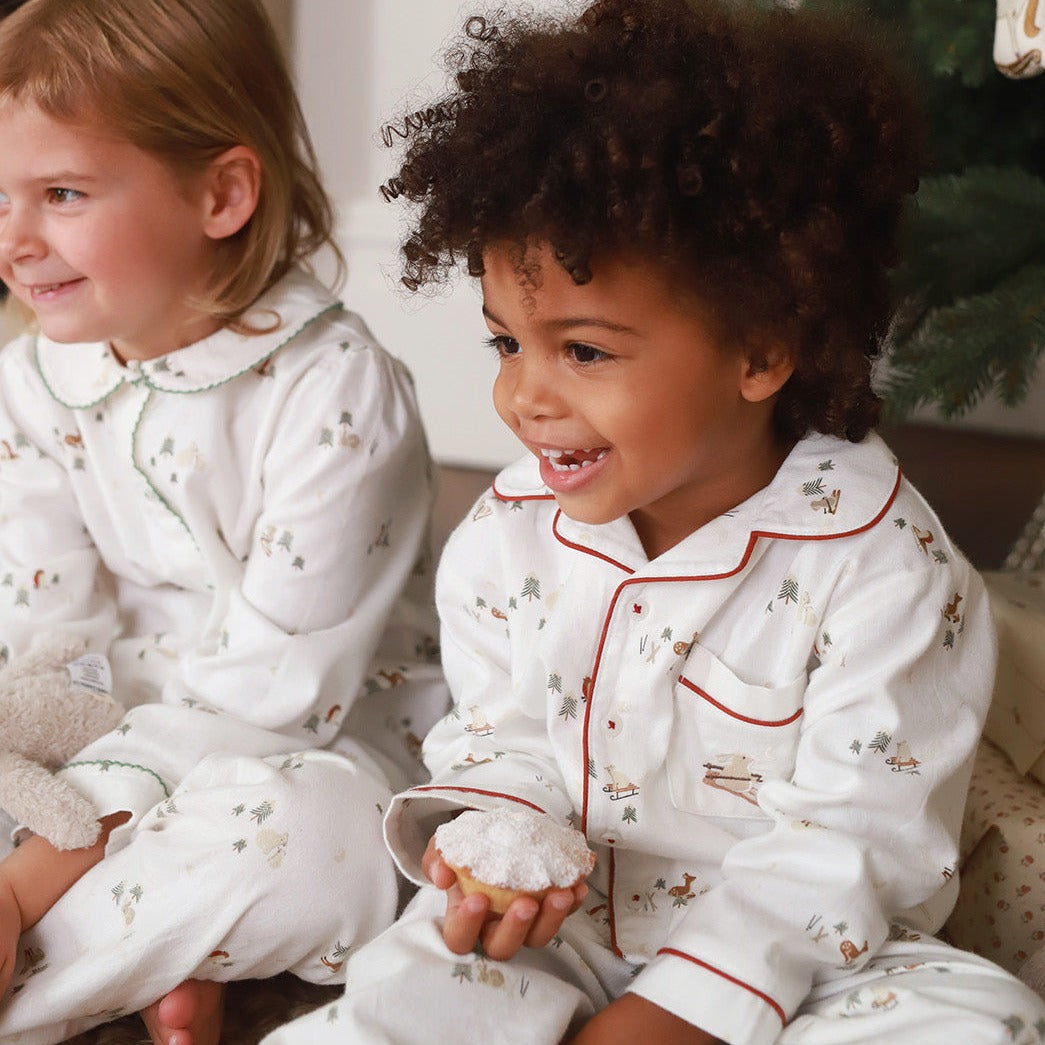 Two children in matching pajamas sitting together, one holding a donut.
