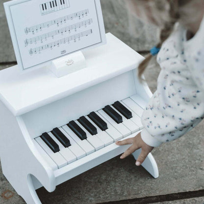 Child outside playing a white toy piano