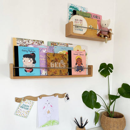 Wooden shelves with books and a plant on a white wall