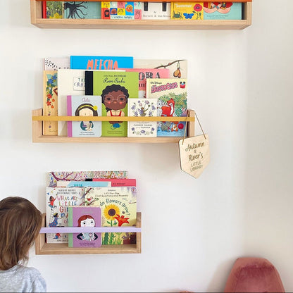 Children's books on wooden shelves against a white wall