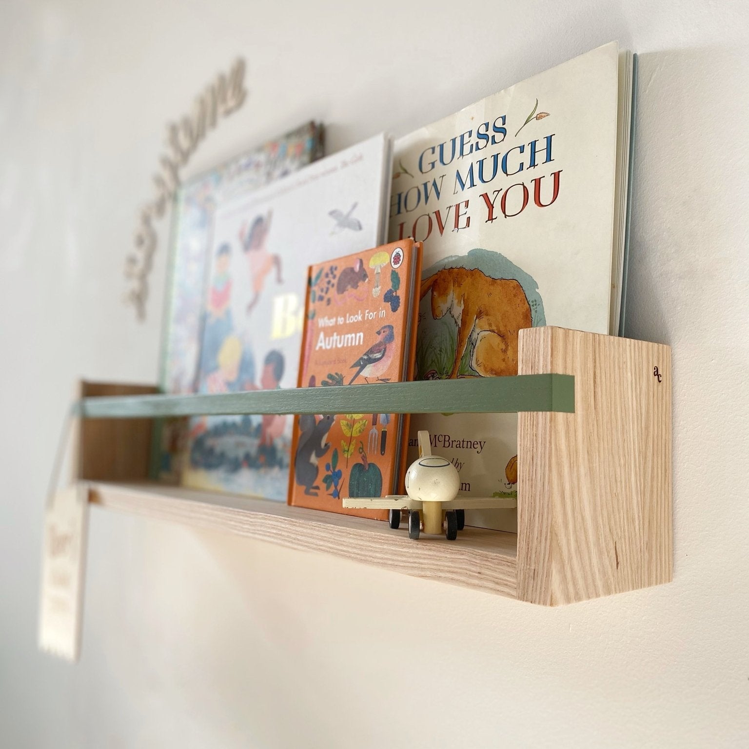 Wooden shelf with children's books on a white wall
