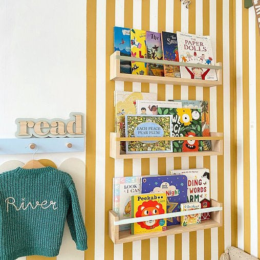 Wooden bookshelf with children's books against a yellow striped wall.