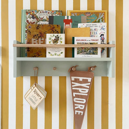 Children's books and a pennant on a shelf against a striped wall.