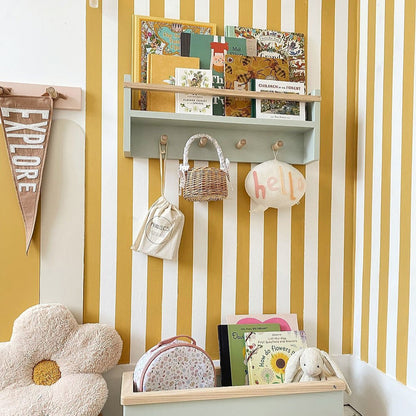 Children's room with a shelf, hooks, and decorative items against a yellow and white striped wall.