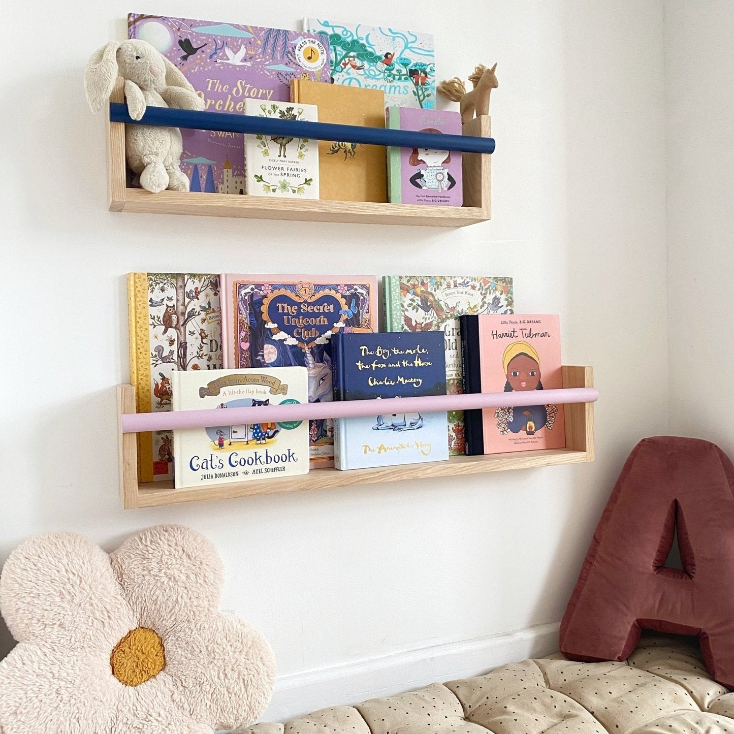 Children's bookshelves with books and toys against a white wall.