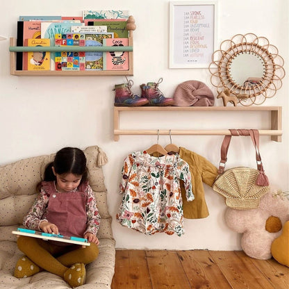 Child reading a book on a couch in a playroom with shelves and toys.