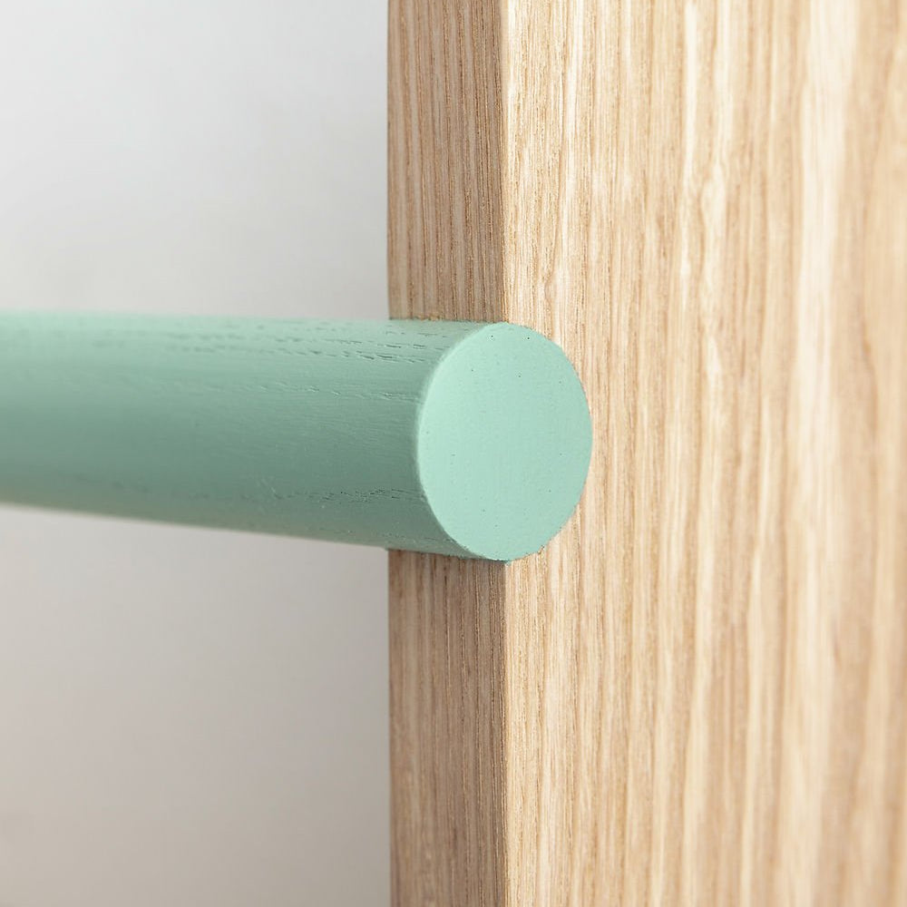 Close-up of a wooden surface with a green cylindrical object on a light gray background