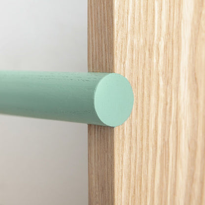 Close-up of a wooden surface with a green cylindrical object on a light gray background