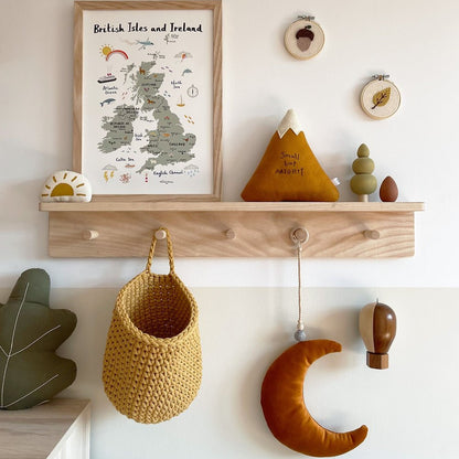 Wooden shelf with decorative items including a framed map, plush toys, and hanging baskets against a light wall.