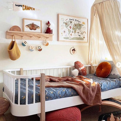 Children's bedroom with a white crib, wooden shelf, and decorative elements.
