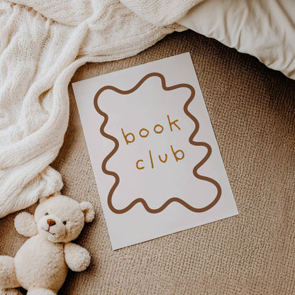 Card with 'book club' text next to a teddy bear on a textured surface