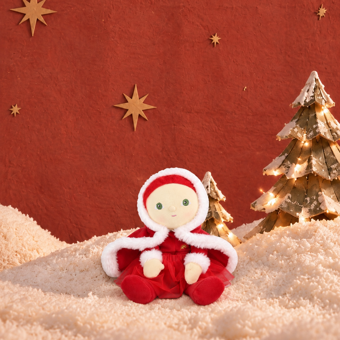 a christmas doll dressed in red with a christmas background.