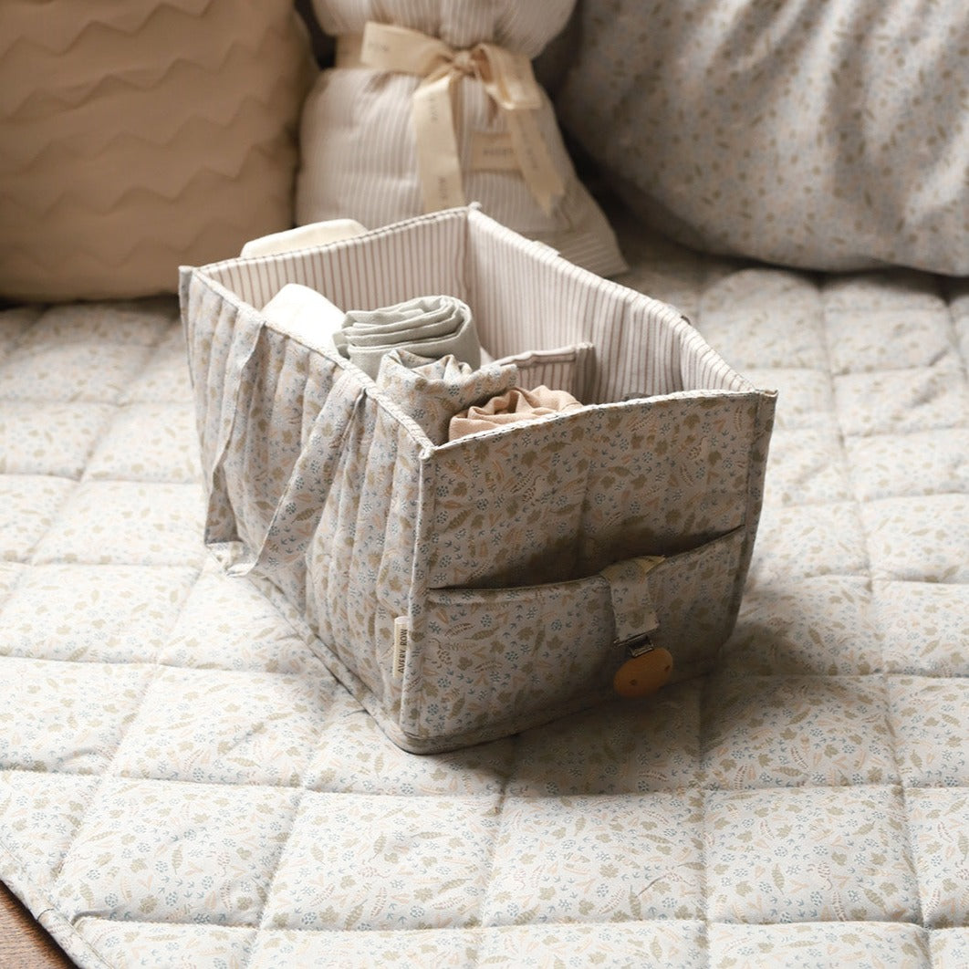 Fabric storage basket with clothes on a quilted surface