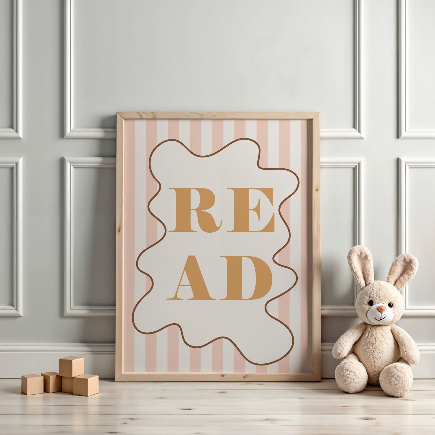 Framed 'READ' poster with a plush bunny and wooden blocks on a light wood floor.