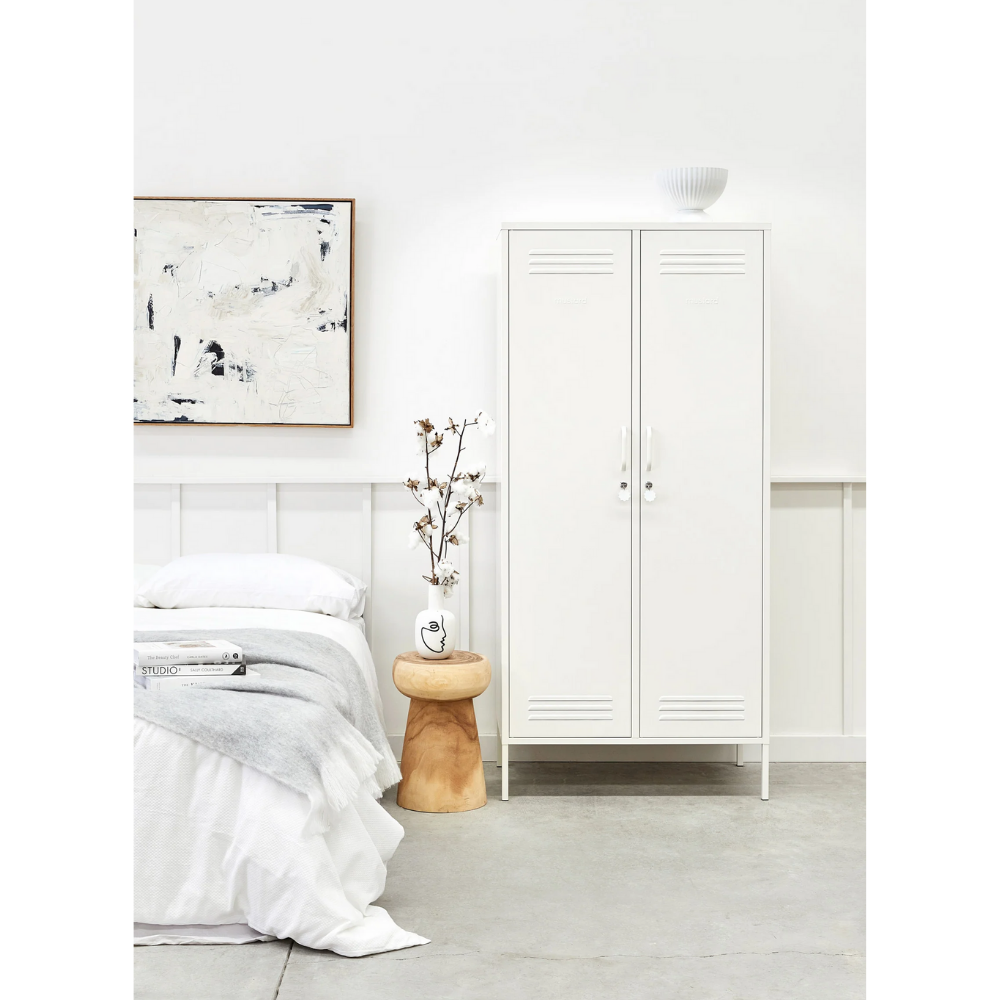 Minimalist bedroom with white bed, abstract art, and wooden side table.