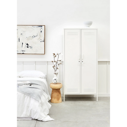 Minimalist bedroom with white bed, abstract art, and wooden side table.