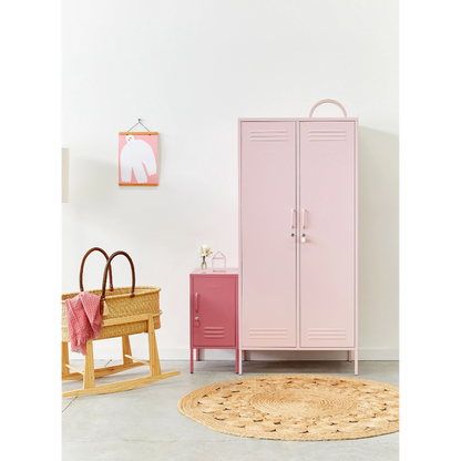 Pink locker in a room with a wooden basket and round rug on a light gray floor.