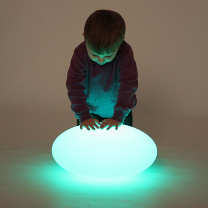 A child standing over a pebble shaped light.