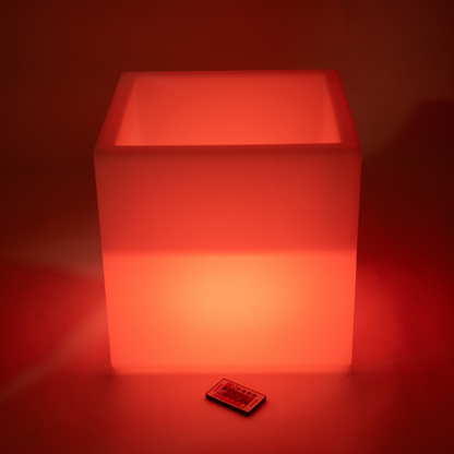 Red illuminated light cube with a remote control on a red background