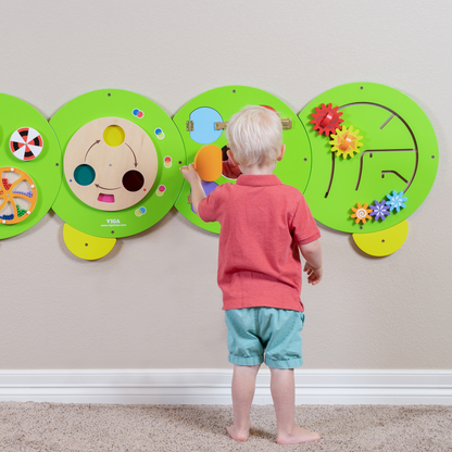 Child interacting with a colourful educational wall panel shaped like a caterpillar