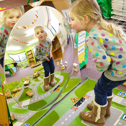Child in a classroom setting looking at themselves in a mirror.