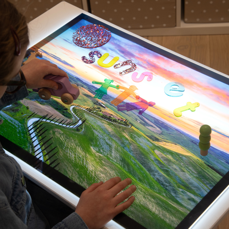 Child interacting with a light panel with a play scene and with a vehicle
