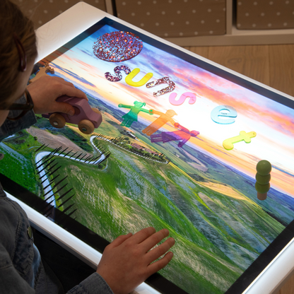 Child interacting with a light panel with a play scene and with a vehicle