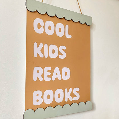 Decorative sign with 'Cool kids read books' text on a plain background