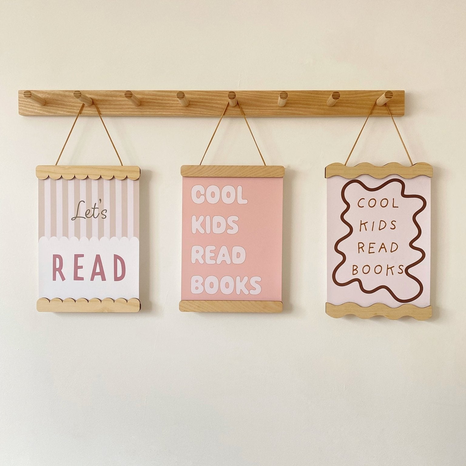 Three motivational signs for children hanging on a wooden rod against a white wall.