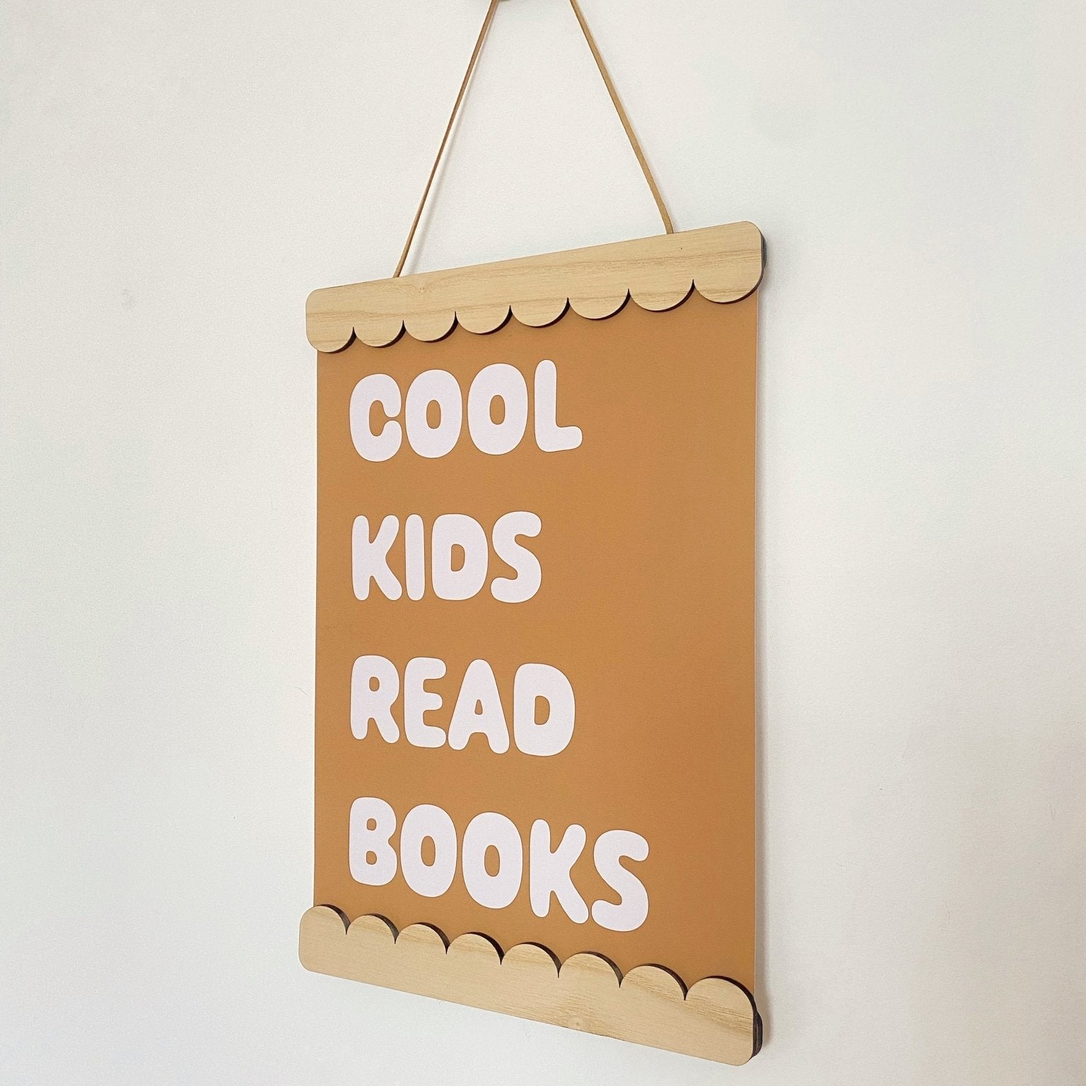 Decorative sign with 'Cool kids read books' text on a plain background