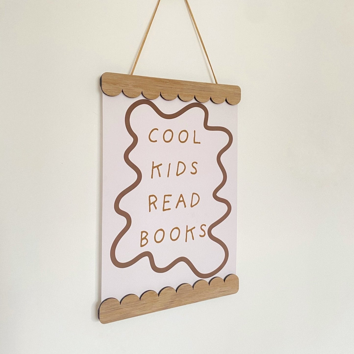 Hanging sign with 'Cool kids read books' text on a plain background