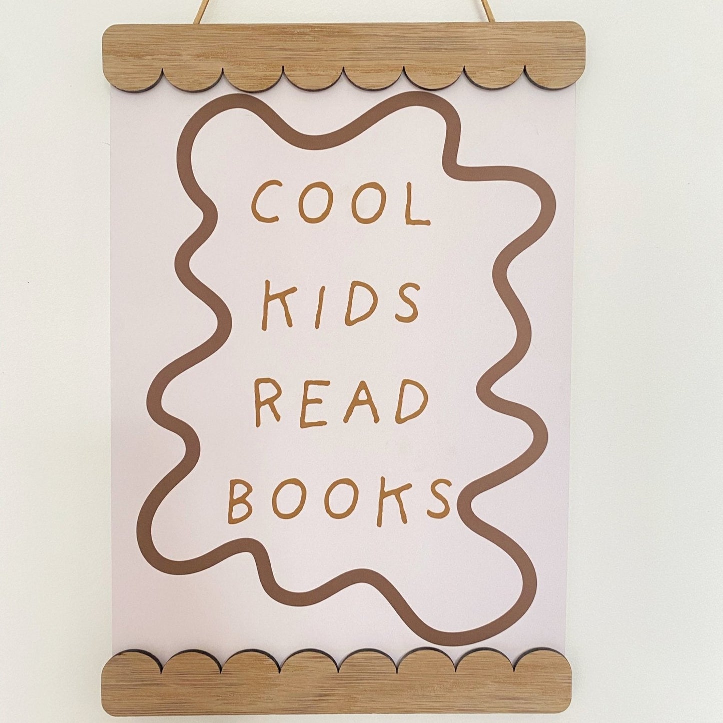 Decorative sign with 'Cool kids read books' text on a plain background