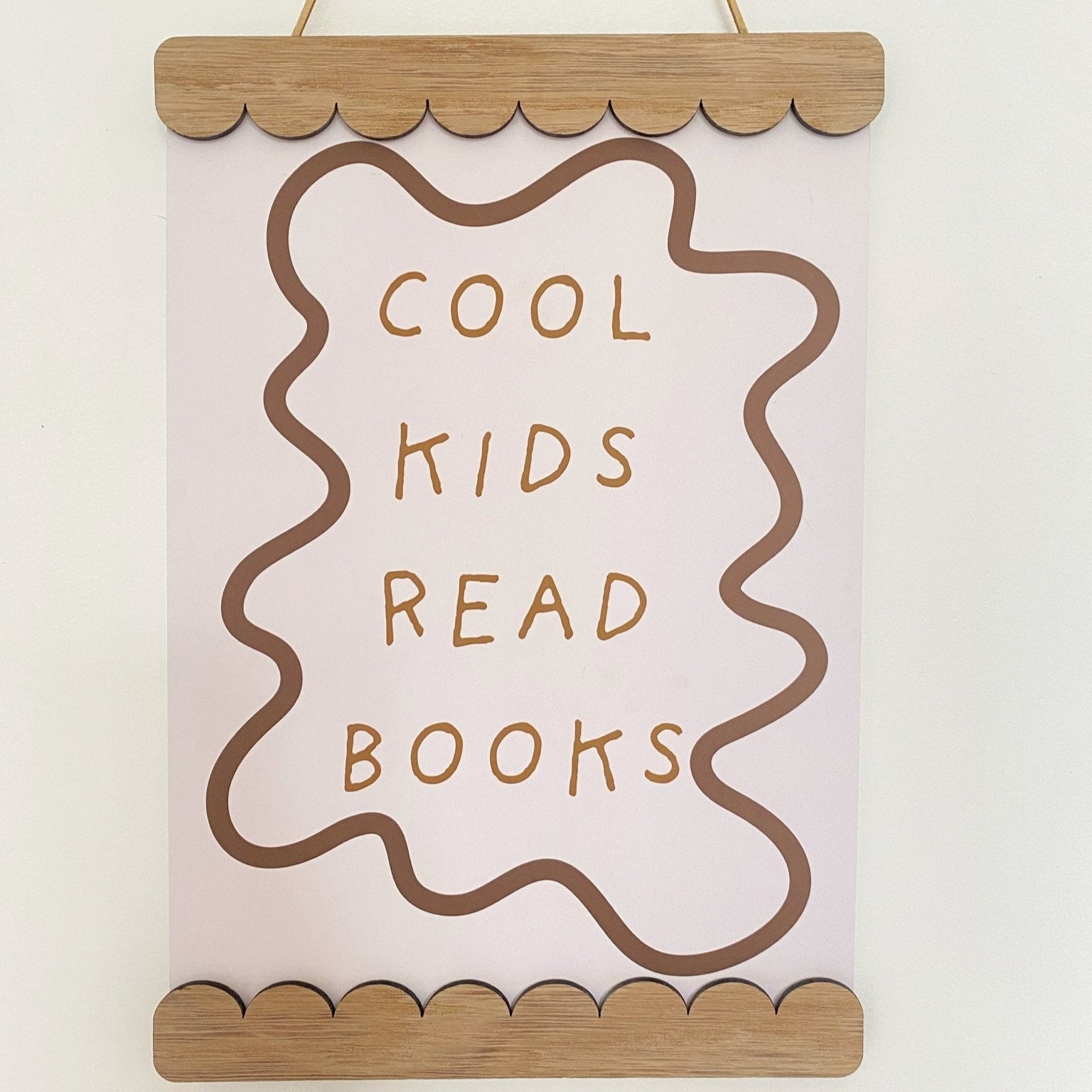 Decorative sign with 'Cool kids read books' text on a plain background